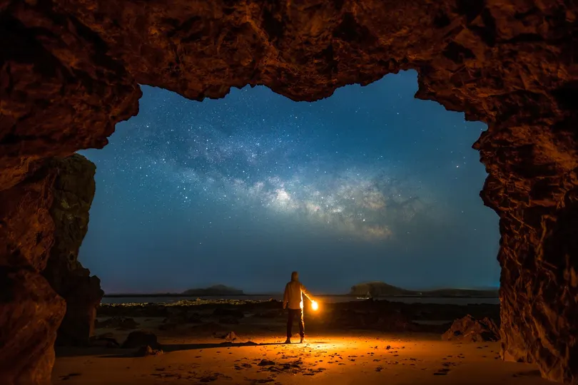 一个夜晚站在洞穴里 天空被星星照亮的男人