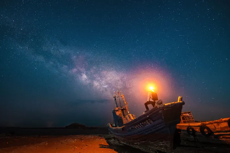 夜晚海滩边的老船 天空中繁星闪烁