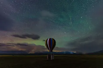 夜空中星星闪烁 热气球在田野上空飞行的景象。
