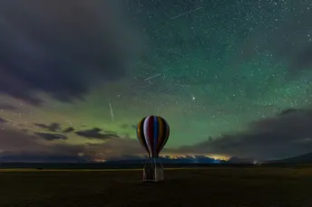 夜空中繁星闪烁 热气球在田野上飞行。