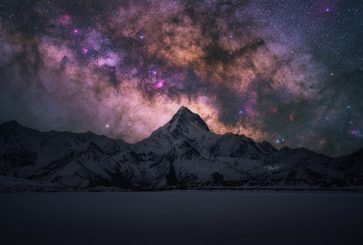 夜晚的山脉上有星星和星系在天空中。
