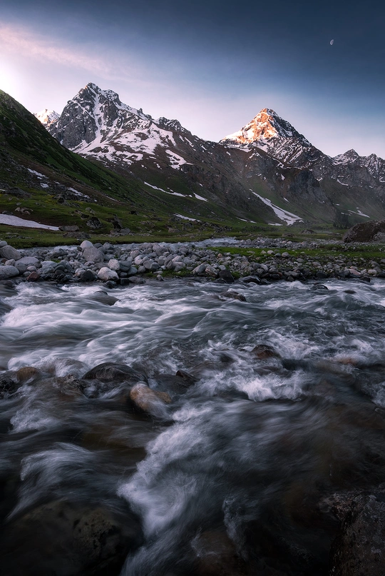 a river flowing through a valley with rocks and mo