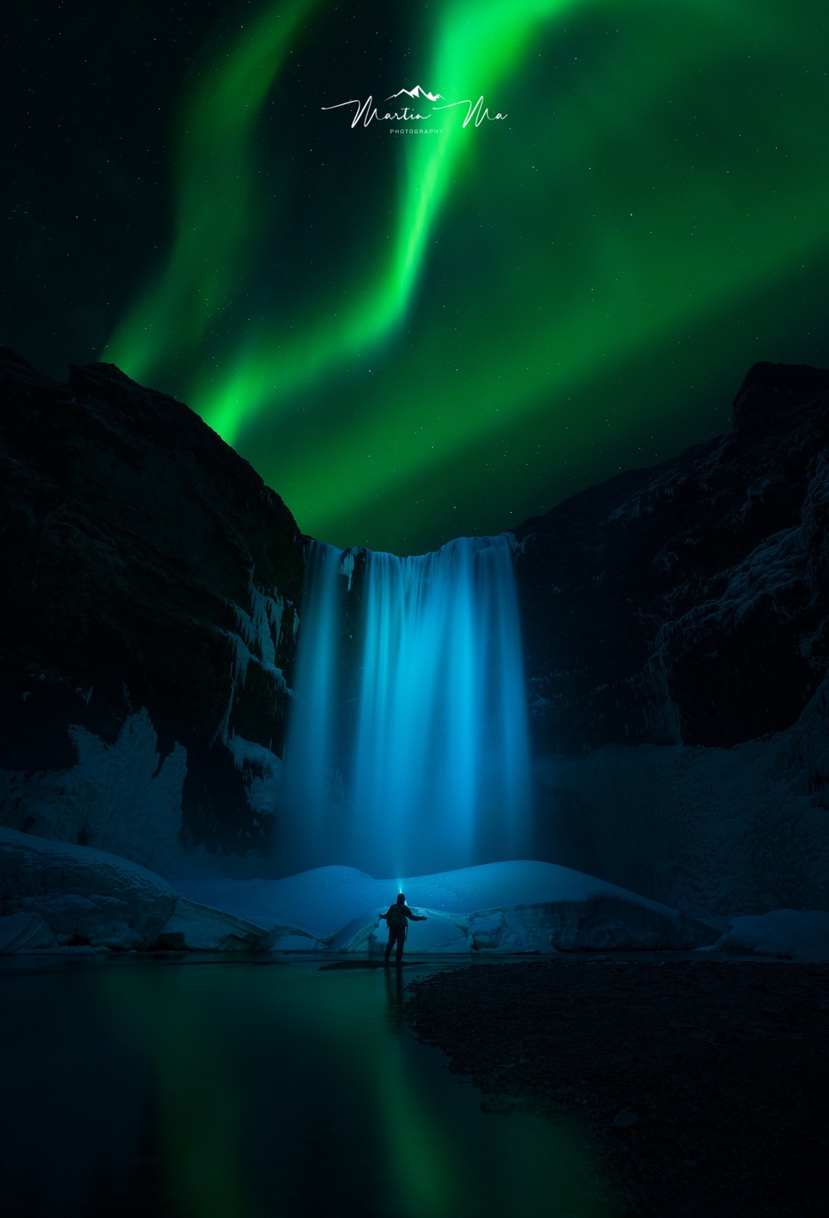 站在瀑布前的一个人 天空中有一个绿色的极光。