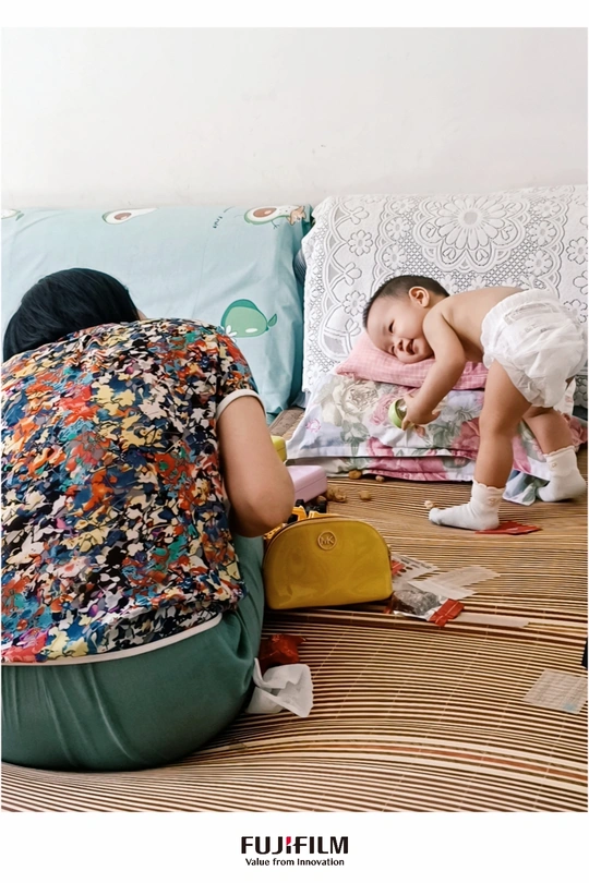 一个年轻女子和一个小孩在地板上一起玩 旁边是床。