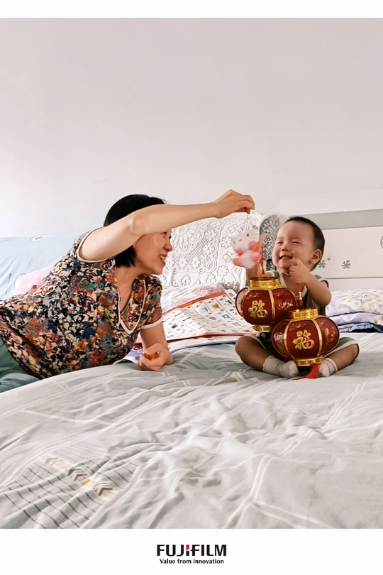 一位妇女坐在床上与婴儿玩耍