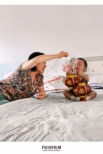 一位妇女坐在床上与婴儿玩耍