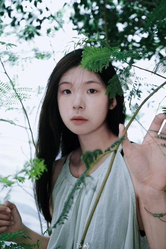 一位年轻女子在森林中拿着一片植物的叶子