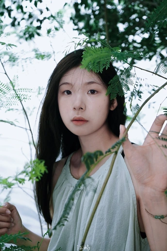 一位年轻女子在森林中拿着一片植物的叶子