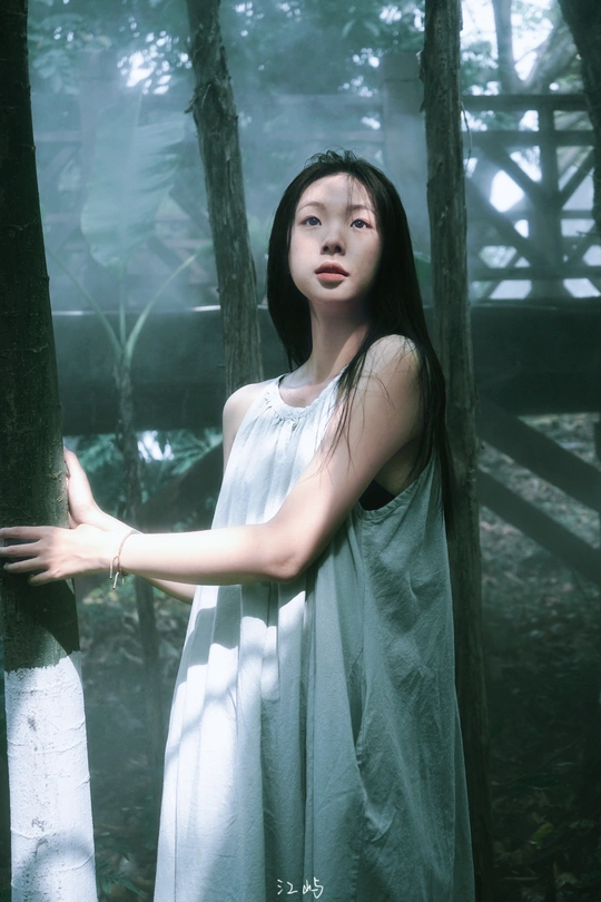 一个穿着白色连衣裙的年轻女子站在森林中