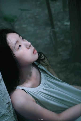 一位年轻女子穿着白色连衣裙坐在森林中的水边