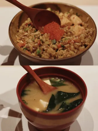 一碗汤 里面有米饭和蔬菜 勺子放在桌子上