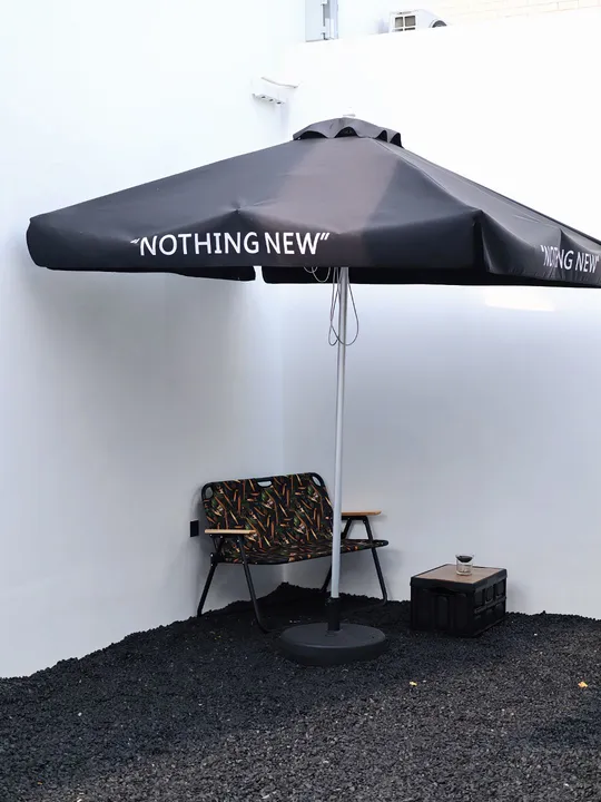 一把黑伞坐在白色墙壁旁边的一张桌子顶部