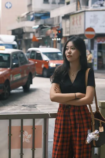 一位年轻女子穿着格子裙在繁忙的街道上摆姿势