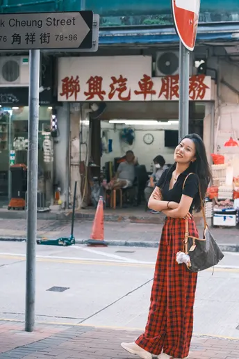 一位穿着格子裙子的年轻女子站在街角的人行道上。