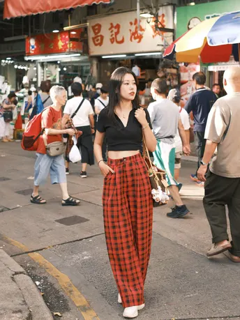 一位穿红裤子的年轻女子站在一条街道的中间