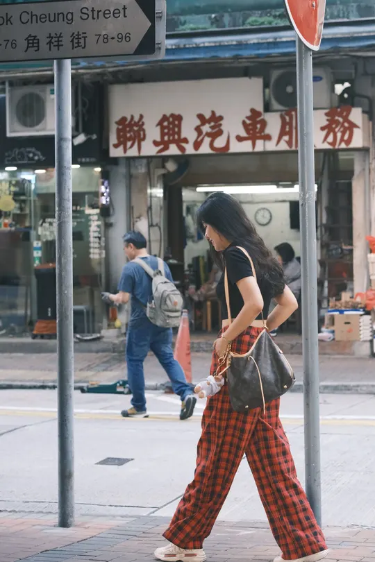 穿格子裤子的年轻女子正在人行道上行走