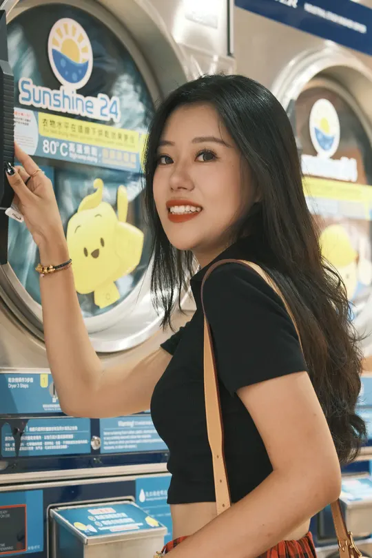 一位年轻女子手持相机站在硬币机前