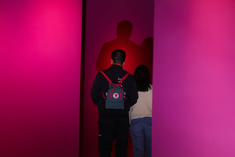 一些人站在一个带粉红色墙壁和红色灯光的房间里