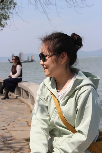 一个戴太阳镜的年轻女子坐在靠近水域的长椅上