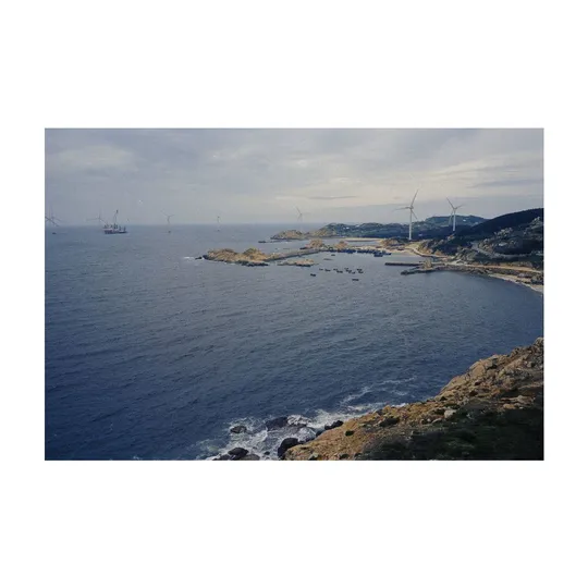 海岸线上的海湾 有船只停泊在水中 沿岸有风车和风力发电厂