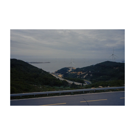 沿着山坡俯瞰海洋和山脉 远处有风车。