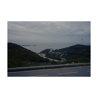 沿着山坡俯瞰海洋和山脉 远处有风车。