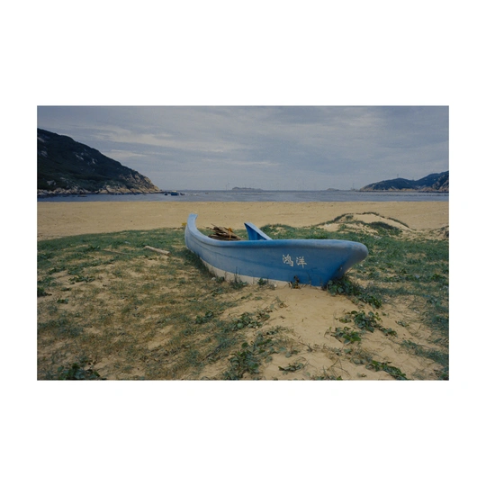 一艘小船停在沙滩上 靠近水边 沙滩上有草和沙子。