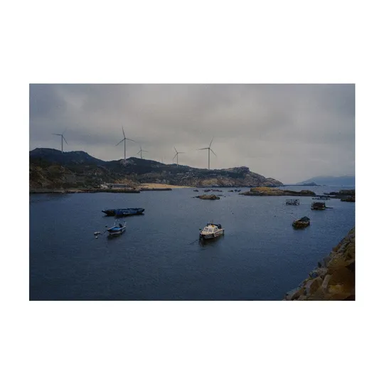 一片水域 湾中有小船 远处有风车。