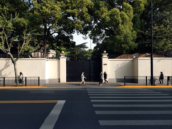 人行道上有白色的大门和人们沿着道路走