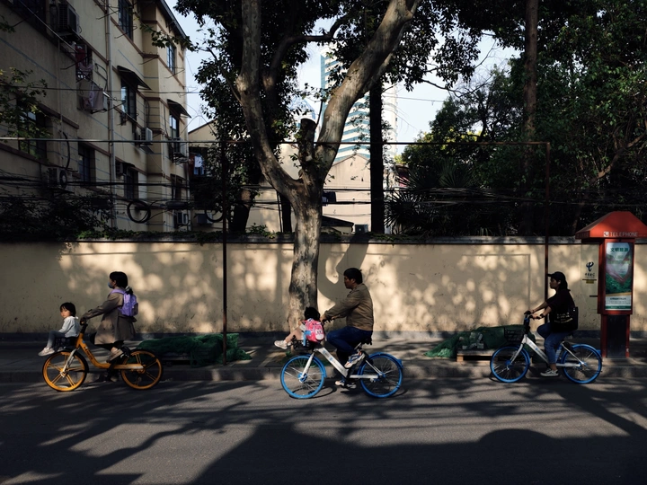 骑自行车的一家人在人行道旁边的一条街道上
