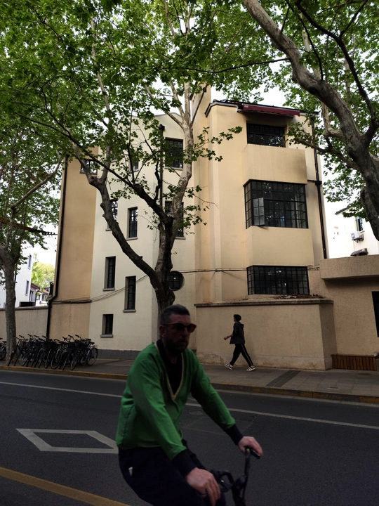 一个人骑自行车沿着树木和建筑物的街道