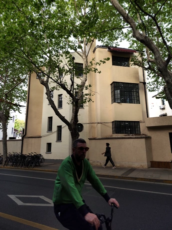 一个人骑自行车沿着树木和建筑物的街道