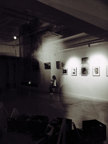 一张黑白照片 展示了一个艺术画廊 画廊的墙壁上挂满了画作 一个人正在拍照。