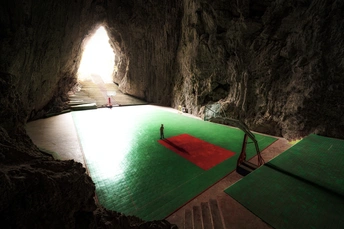 一个黑暗的洞穴 地面上铺着绿色的垫子 入口处有一盏灯。