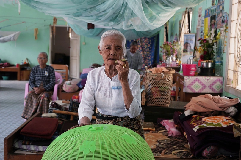 一个老人站在一个有绿色球坐在桌子上的房间里