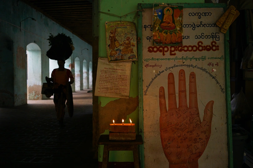 一个人骑自行车在黑暗的房间里 一个人拿着点燃的蜡烛站在一个标志前面。