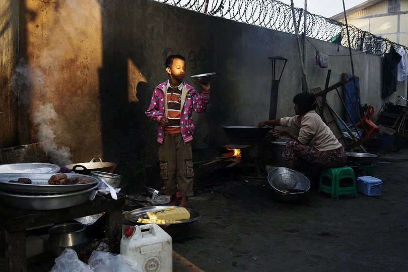 有些人正在建筑旁边的一条小巷子里用罐子做饭。