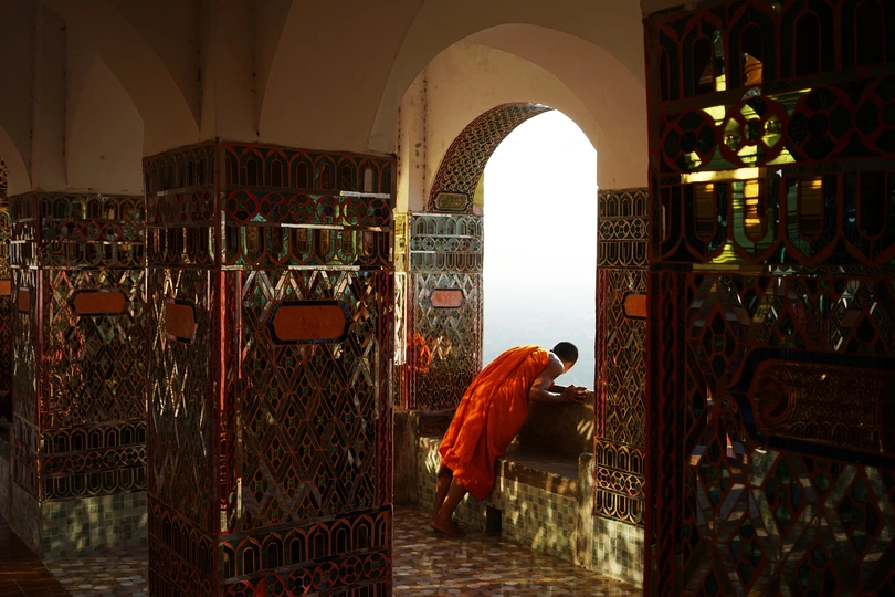 一个人穿着橙色长袍站在一个房间里看着某物