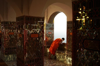 一个人穿着橙色长袍站在一个房间里看着某物