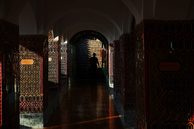 一条长走廊 地面和墙壁都铺有瓷砖 走廊里设有拱门和门上的灯光。