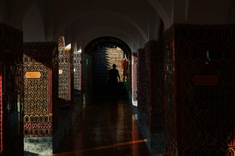 一条长走廊 地面和墙壁都铺有瓷砖 走廊里设有拱门和门上的灯光。