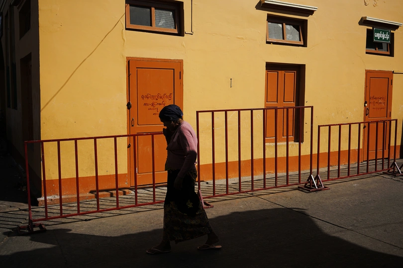 一个人走在黄色建筑旁边的一条街道上