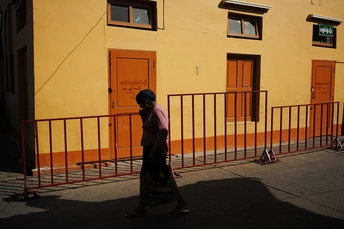 一个人走在黄色建筑旁边的一条街道上