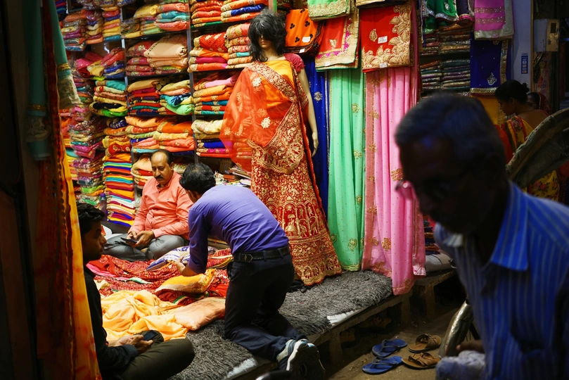 一个男人和一个女人在一个多彩的商店里购物 商店里有各种颜色的布料 人们正在注视着他们。