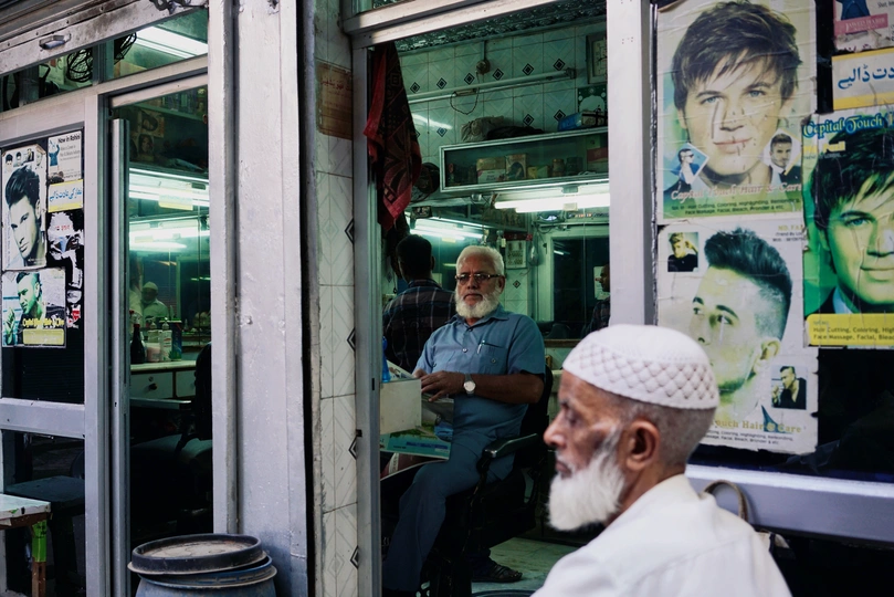 一个老人坐在理发店窗口