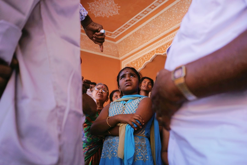 一个男子在一个房间里举起一个年轻女孩 其他人站在那里观看新娘和新郎。