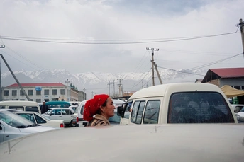 一位穿红衣服的女士驾驶一辆白色货车穿过被雪覆盖的山脉街道