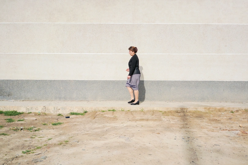 一名年轻男子和一名年轻女子走过一条街道 经过一道混凝土墙。