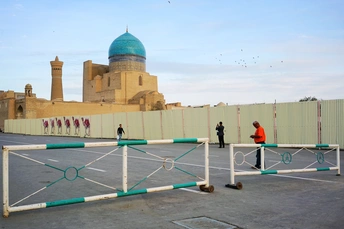 蓝色圆顶建筑在围栏和障碍物后面 人们路过。