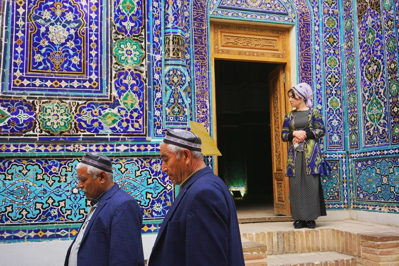 一些男人站在一栋建筑前 墙壁和门上都有彩色瓷砖。